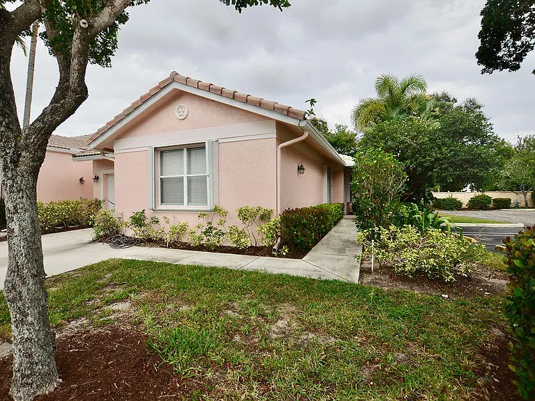 Port St. Lucie home with tropical landscaping and palm trees