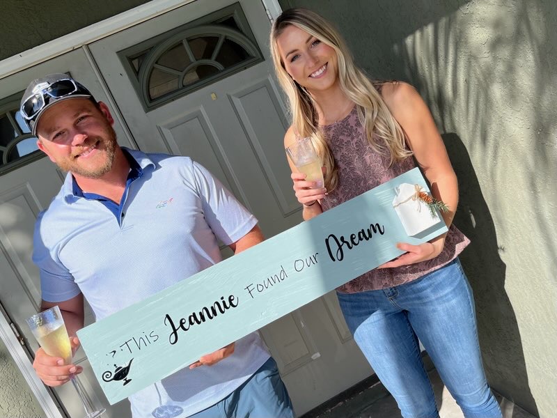 Buyers outside their new Port St. Lucie home holding a sign that reads This Jeannie Found Our Dream